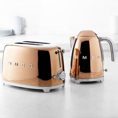 two metallic toasters sitting on top of a counter