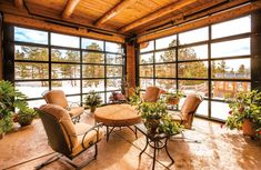 a living room filled with lots of furniture next to large windows and potted plants