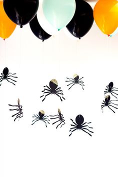 spider balloons are hanging from the ceiling with black, white and orange balloons attached to them