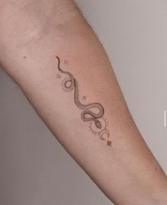 a snake tattoo on the arm with stars and moon in the sky above it's head