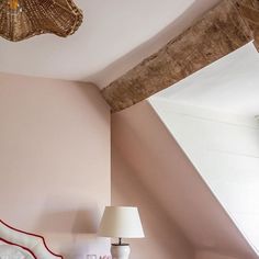 a bedroom with pink walls and white bedding has a basket hanging from the ceiling