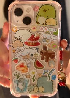 someone holding up their phone case with many stickers on it