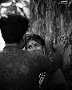 black and white photograph of two people touching a tree