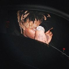 a man with dreadlocks is looking at his cell phone in the back seat of a car