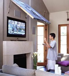 a man standing in front of a flat screen tv next to a fire place and couch