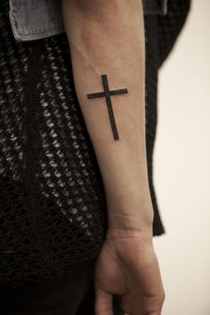 a person with a cross tattoo on their arm