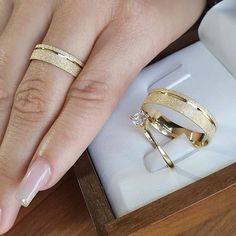 a woman's hand with two gold rings on top of her finger and one in the