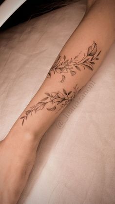 a woman's arm with flowers and leaves tattoo on the left side of her leg