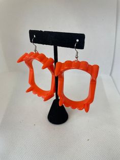 an orange pair of glasses is hanging from a black stand on a white background,