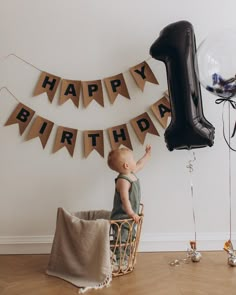 a baby sitting on a chair in front of a birthday banner