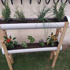 an outdoor planter made out of pipes with plants growing in it and some flowers on top