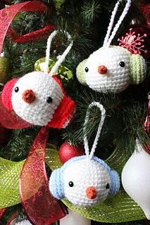 three crocheted birds hanging from a christmas tree with red and green ribbons on it