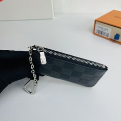 This Damier canvas pouch holds loose change and keys and slips easily into a handbag or coat pocket. Size: 12×7cm Black Pouch With Coin Pocket For Daily Use, Luxury Black Coin Purse With Interior Key Chain Holder, Everyday Black Bag With Key Clip, Black Bag With Key Clip For Everyday Use, Black Bags With Key Clip For Everyday Use, Black Coin Purse With Zipper Pocket, Black Bag With Key Clip As Gift, Black Coin Purse With Zipper Pocket As A Gift, Black Travel Coin Purse With Key Clip