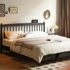 a bed sitting in a bedroom on top of a wooden floor next to a window