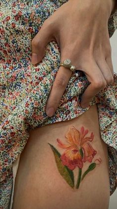 a woman with a flower tattoo on her stomach is holding onto the side of her thigh