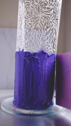 a purple cake sitting on top of a white plate next to a pink candle holder