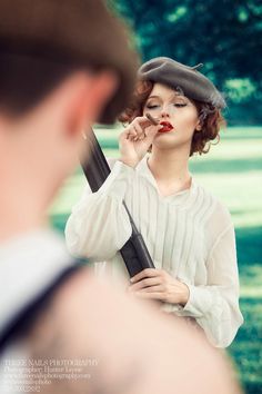 a woman brushing her teeth while standing in front of a man with a hat on