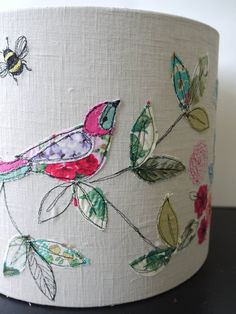 a lamp shade with birds and flowers on the fabric, sitting on a black table