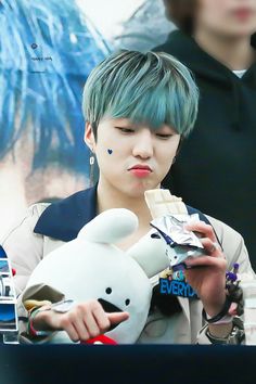 a person with blue hair holding a stuffed animal