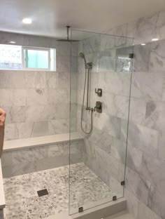 a person taking a photo of a bathroom with marble walls and tile flooring on the shower