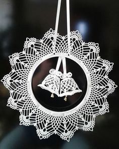 a white ornament hanging from a string with two bells on it's side