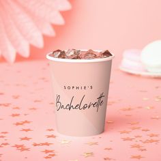 a pink cup filled with chocolate chips on top of a table next to a star shaped object