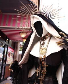 a mannequin dressed in black and white with gold chains on it's head