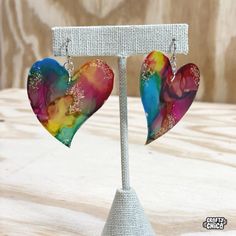 two heart shaped earrings are hanging from a stand