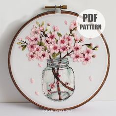 a glass jar filled with pink flowers sitting on top of a white table next to a wall