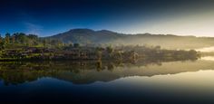 the sun is setting over a lake with houses on it and mountains in the background