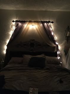 a bed that has some lights on the headboard and is lit up with fairy lights