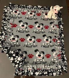 a stuffed animal sitting on top of a cloth covered tablecloth with dogs and words