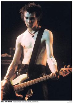 a shirtless man playing a guitar on stage