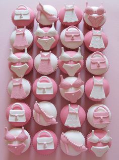 pink and white cupcakes are arranged in the shape of baby's clothes