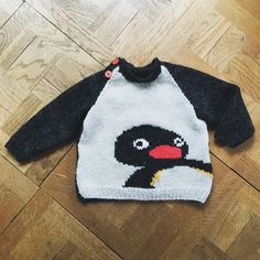 a sweater with an image of a bird on it is laying on the floor next to a wooden floor