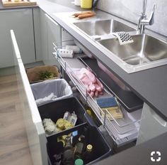 an organized kitchen drawer is shown with cleaning supplies and other items in the bins