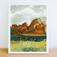 a painting of mountains and water with yellow flowers in the foreground, on a wooden table