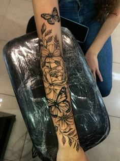 a woman's arm with flowers and butterflies on it