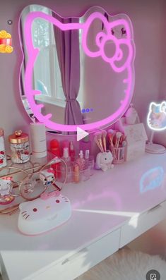 a pink hello kitty mirror sitting on top of a white desk next to a window