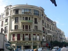 a large white building with many windows and balconies on the top floor, next to a busy street