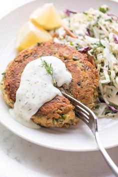 a plate with crab cakes, coleslaw and lemon wedges on the side