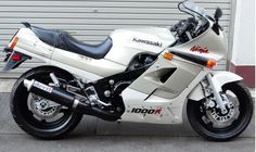 a white motorcycle parked in front of a garage door