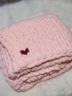 a pink knitted blanket with a heart on it