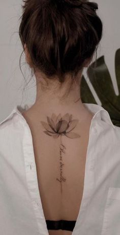 the back of a woman's neck with a lotus tattoo