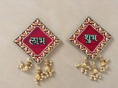 two pairs of gold and red earrings with the word india written in large letters on them