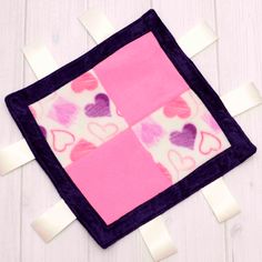 a pink and purple patchwork square with hearts on it, taped to the wall