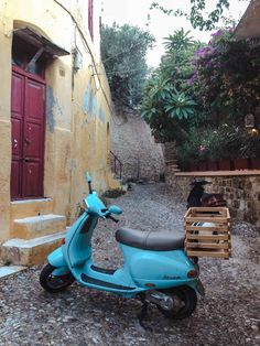 a blue scooter parked on the side of a road next to a building