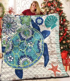 a woman is holding up a quilt with a turtle on it and starfishs in the background