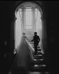 the bride and groom are walking down the stairs at their wedding ceremony in black and white