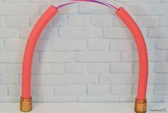 two pink and gold colored arch stands against a white brick wall